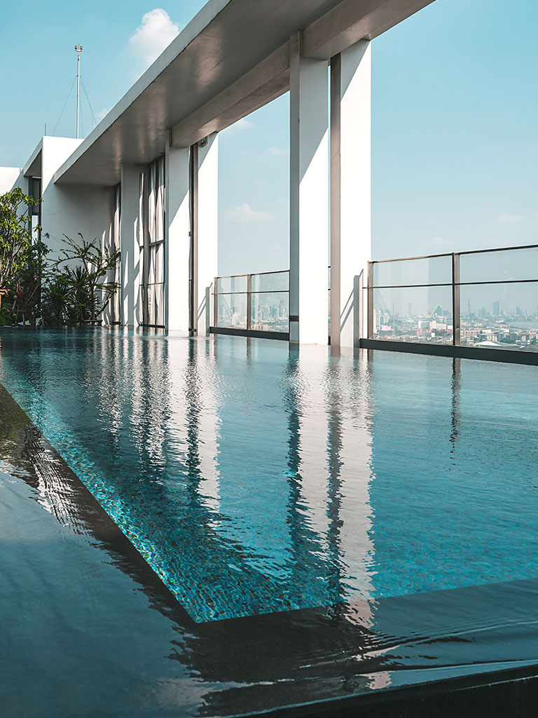 Modernity. Infinity swimming pool on a rooftop with view of the city. Luxury resort, spa, urban, city concept. Vertical shot